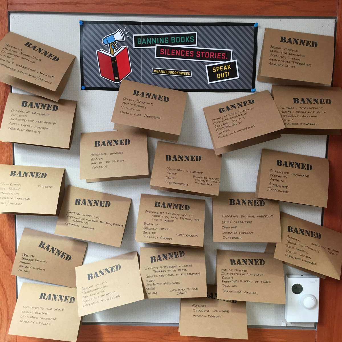 Cardboard notecards with reasons why books were challenged written on them