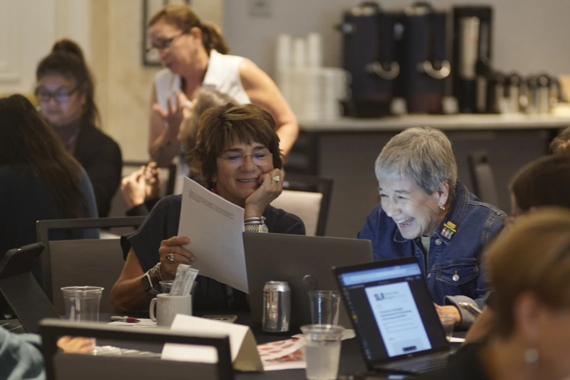 school librarians sit around a table with laptops and books working together