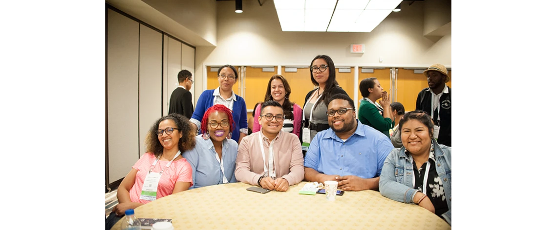 Engage with Colleagues with Core. A group of 6 women and 2 men posed around a table smiling