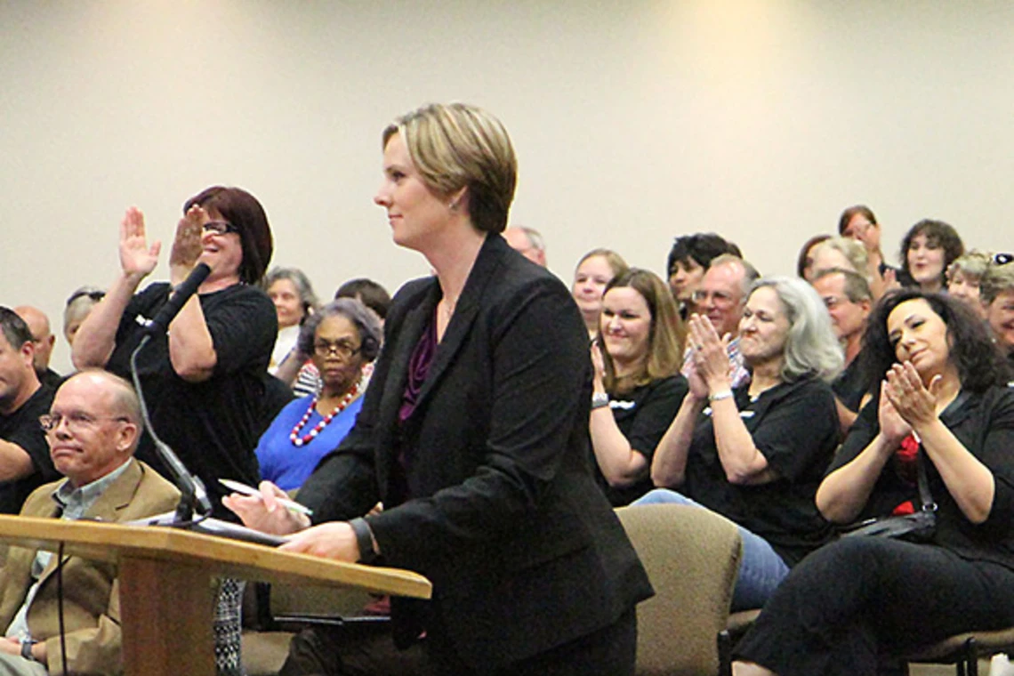 Librarian speaking at a board meeting. Attendees applaud.