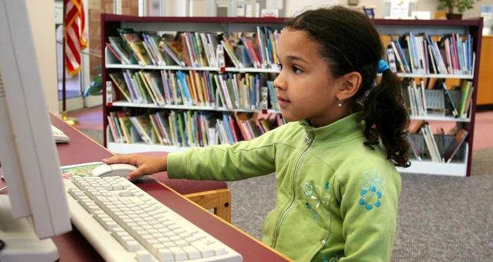 Little girl uses a computer at the library
