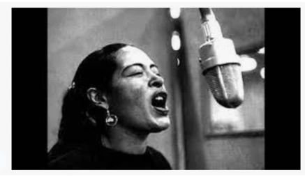 Billie Holiday signing passionately into a microphone.